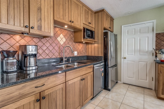 kitchen featuring backsplash, appliances with stainless steel finishes, sink, dark stone countertops, and light tile floors