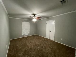 empty room with dark carpet, ceiling fan, and ornamental molding