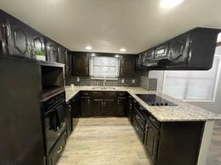 kitchen with sink, light stone counters, backsplash, black appliances, and light wood-type flooring