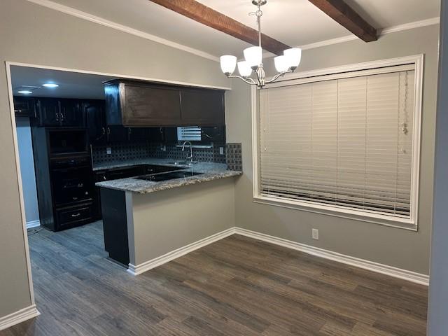 kitchen featuring beam ceiling, dark wood-type flooring, backsplash, a chandelier, and pendant lighting