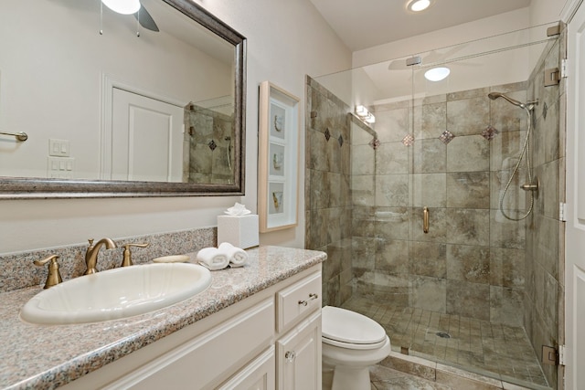 bathroom featuring vanity, ceiling fan, a shower with door, and toilet