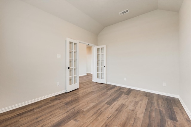 empty room featuring dark hardwood / wood-style flooring, vaulted ceiling, and french doors