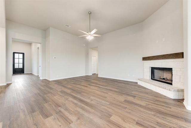 unfurnished living room featuring wood-type flooring, ceiling fan, and a fireplace