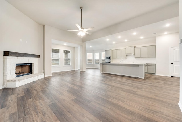 unfurnished living room with ceiling fan, a fireplace, and hardwood / wood-style floors