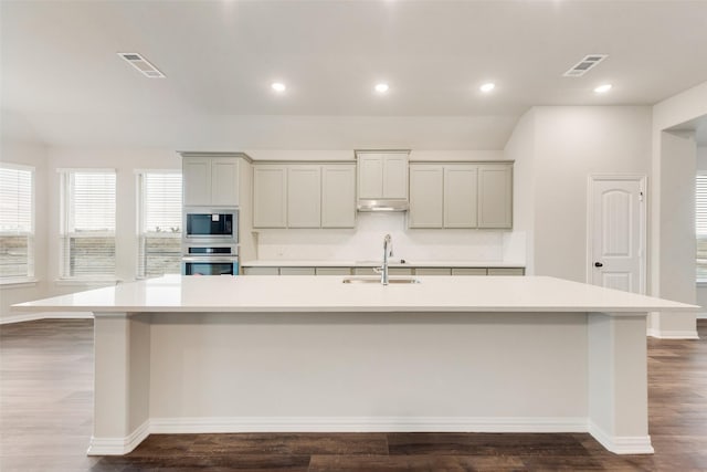 kitchen featuring a large island, sink, hardwood / wood-style floors, built in microwave, and oven