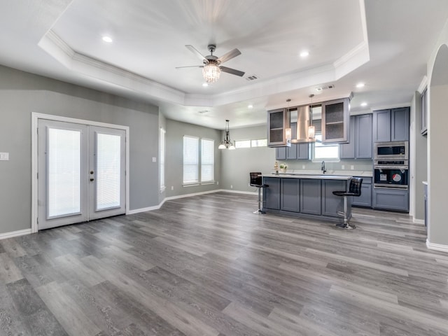 kitchen featuring wood-type flooring, a tray ceiling, a breakfast bar area, and appliances with stainless steel finishes