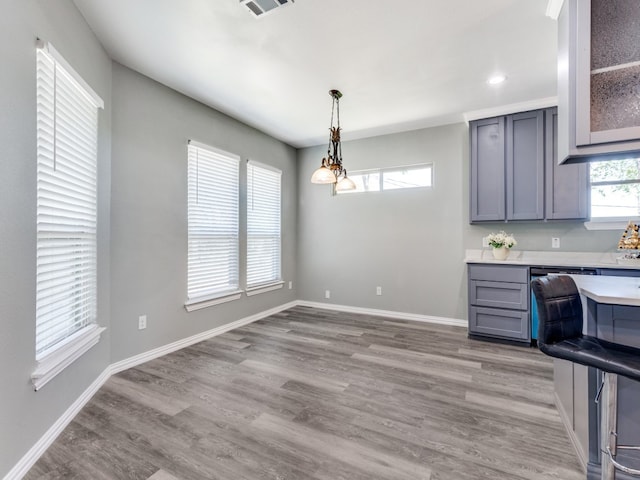 kitchen with gray cabinetry, hardwood / wood-style floors, and decorative light fixtures