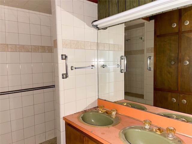 bathroom featuring double sink, a shower with door, and vanity with extensive cabinet space