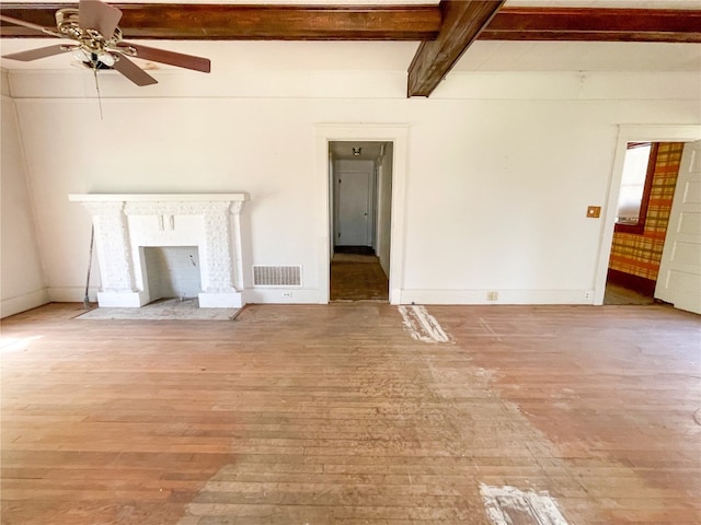 unfurnished living room featuring beam ceiling, ceiling fan, and light wood-type flooring