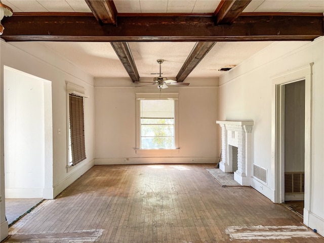 unfurnished living room with a fireplace, ceiling fan, wood-type flooring, and beamed ceiling