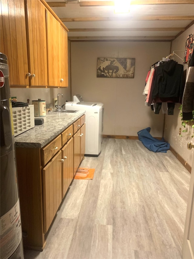 washroom featuring light hardwood / wood-style flooring, water heater, sink, cabinets, and independent washer and dryer