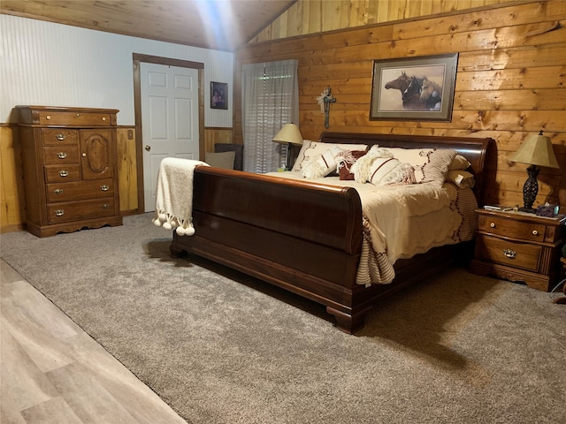 bedroom with wood walls, carpet floors, and vaulted ceiling