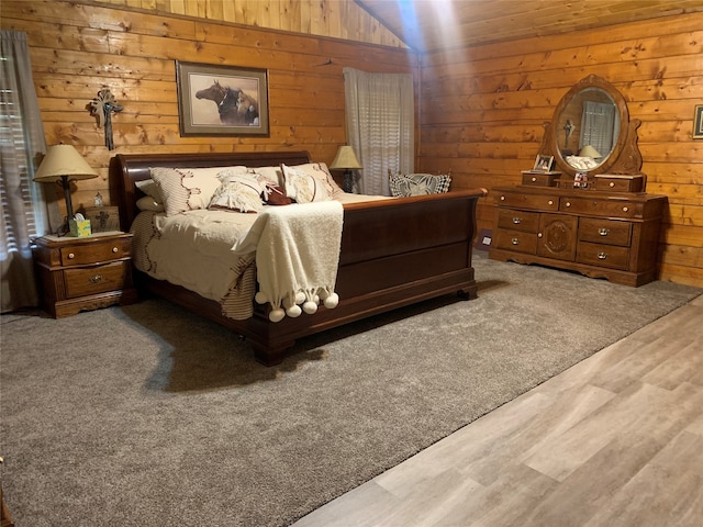 bedroom with wooden walls, lofted ceiling, and hardwood / wood-style floors