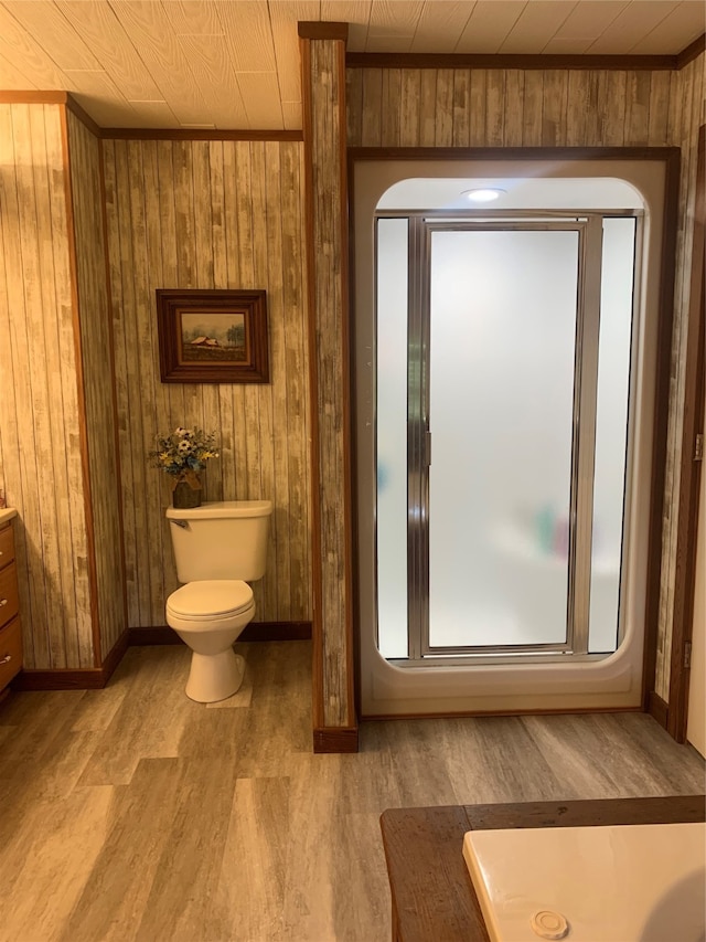 bathroom featuring wood-type flooring, wood walls, toilet, and vanity