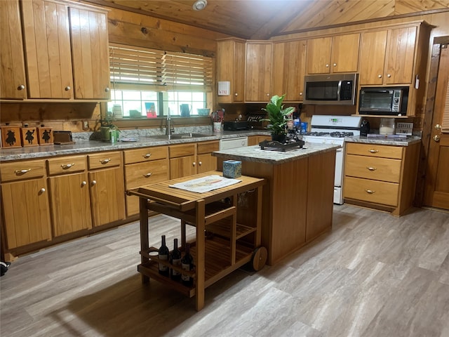 kitchen with wood walls, light hardwood / wood-style floors, a kitchen island, and white appliances