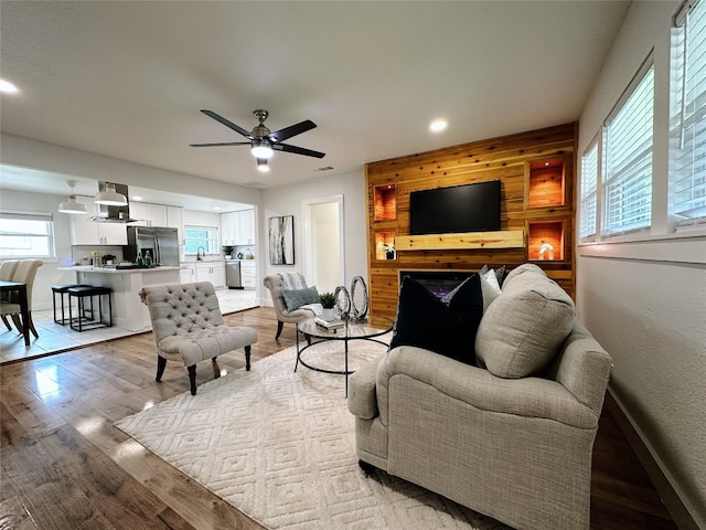 living room featuring wood walls, ceiling fan, and light wood-type flooring