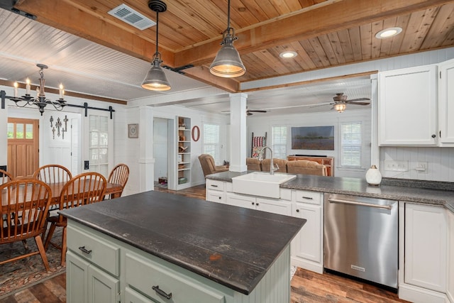 kitchen with pendant lighting, dark hardwood / wood-style flooring, beamed ceiling, stainless steel dishwasher, and a barn door