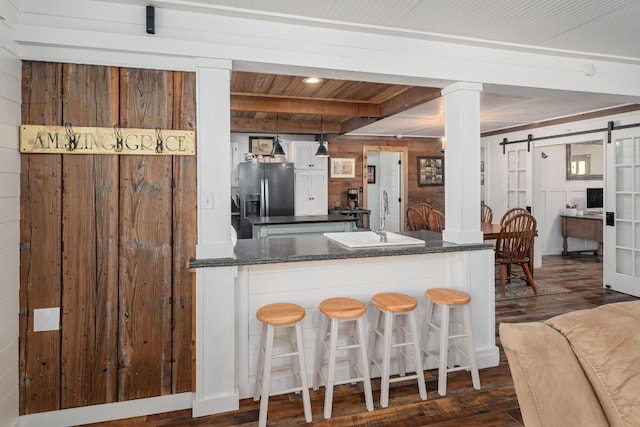 kitchen with pendant lighting, sink, a barn door, stainless steel refrigerator with ice dispenser, and dark hardwood / wood-style floors