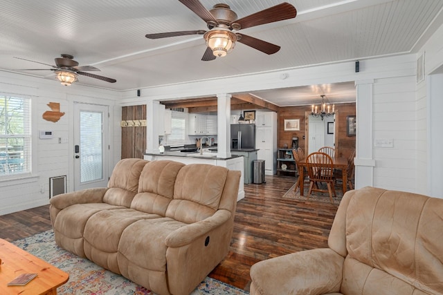 living room with wood walls, dark hardwood / wood-style floors, and ceiling fan with notable chandelier