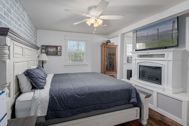 bedroom featuring a high end fireplace, ceiling fan, and dark wood-type flooring