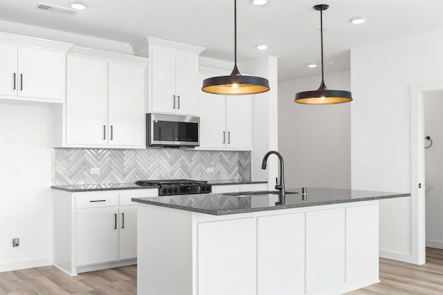 kitchen with white cabinets, a kitchen island with sink, and sink