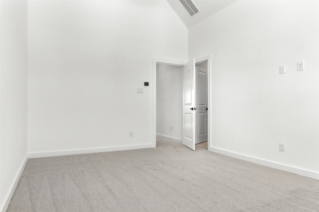 unfurnished room with light carpet and high vaulted ceiling