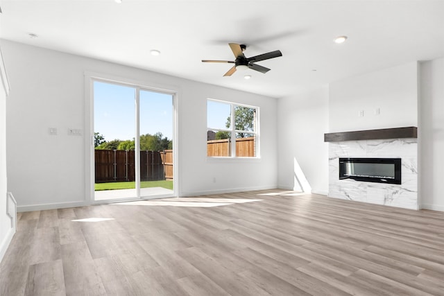 unfurnished living room with light wood-type flooring, a fireplace, and ceiling fan