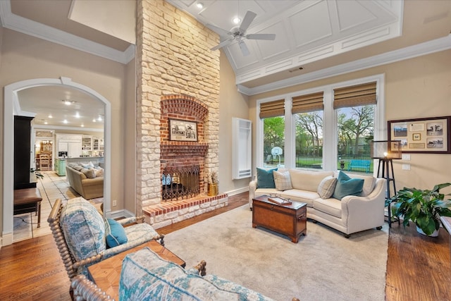 living room with ceiling fan, light wood-type flooring, ornamental molding, and a fireplace