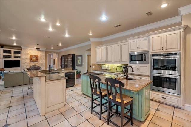 kitchen with sink, a center island with sink, stone countertops, and appliances with stainless steel finishes