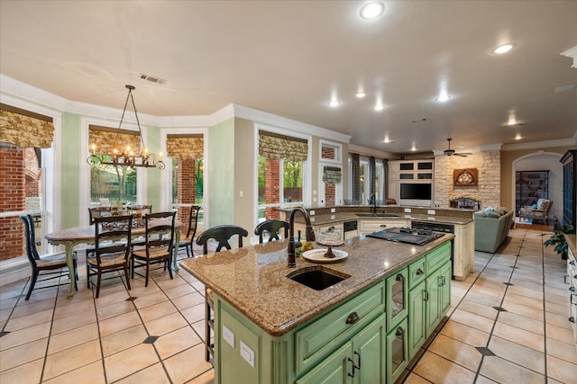 kitchen with a kitchen island with sink, pendant lighting, ornamental molding, stone counters, and green cabinetry