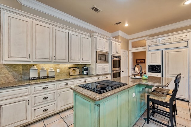 kitchen featuring dark stone countertops, backsplash, an island with sink, and light tile floors