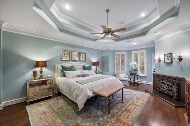 bedroom featuring dark hardwood / wood-style flooring, crown molding, ceiling fan, and a raised ceiling