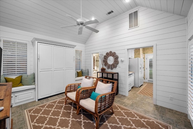 living area with ceiling fan, high vaulted ceiling, and dark tile floors