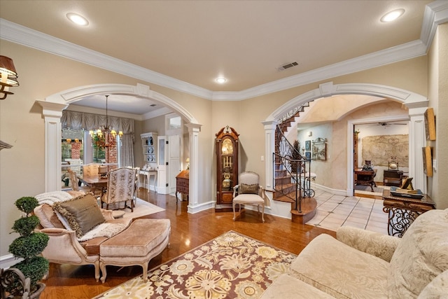 tiled living room with an inviting chandelier, crown molding, and ornate columns