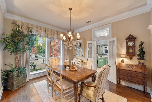 dining area with an inviting chandelier, dark wood-type flooring, and ornamental molding