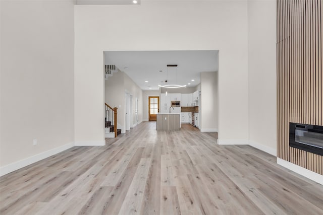 unfurnished living room featuring sink and light wood-type flooring