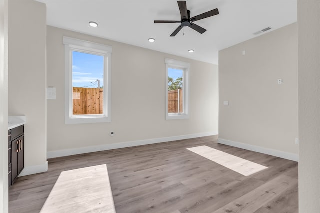 unfurnished living room with light hardwood / wood-style flooring, ceiling fan, and plenty of natural light