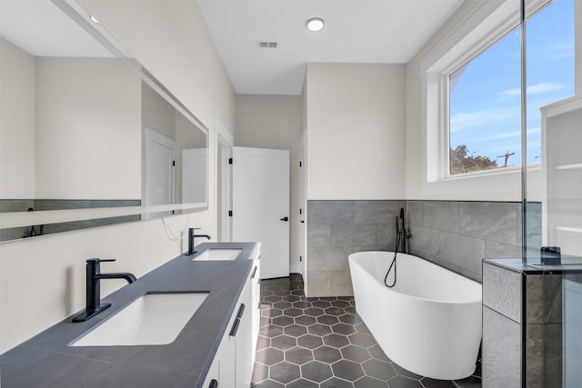 bathroom featuring tile walls, a tub, tile patterned floors, and double sink vanity