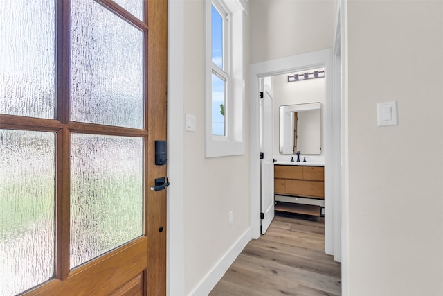 corridor with sink, light wood-type flooring, and a wealth of natural light