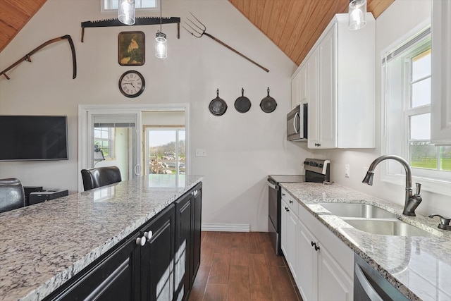 kitchen with white cabinets, stainless steel appliances, dark cabinetry, and decorative light fixtures