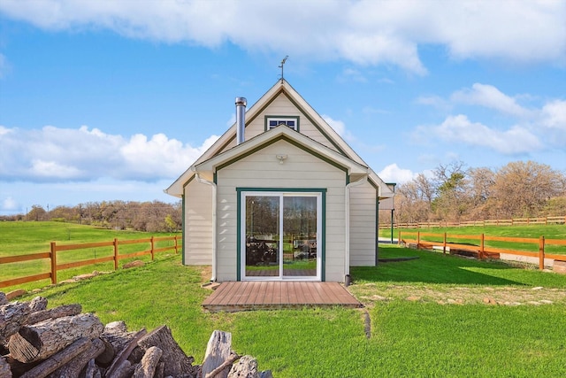 rear view of property with a yard, a rural view, and an outdoor structure