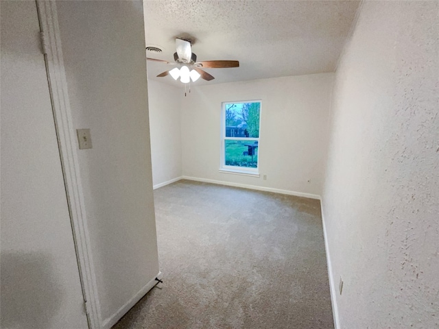 carpeted spare room featuring ceiling fan and a textured ceiling