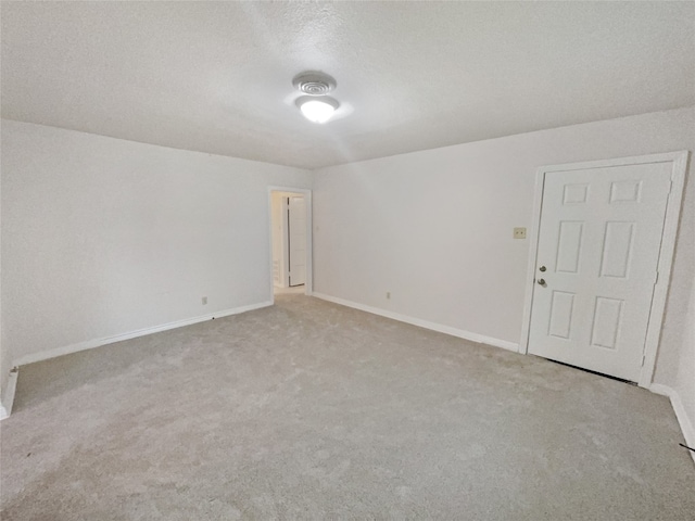 spare room featuring light carpet and a textured ceiling