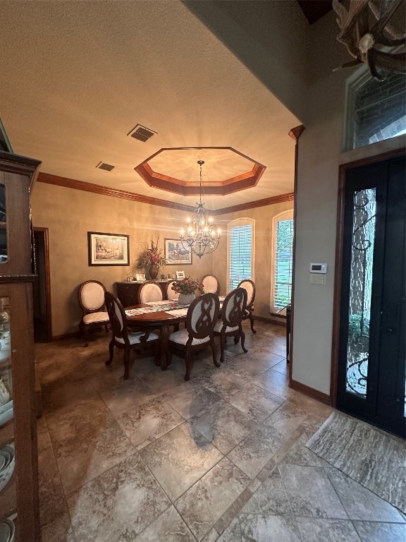 tiled dining space featuring ornamental molding, french doors, a chandelier, and a raised ceiling