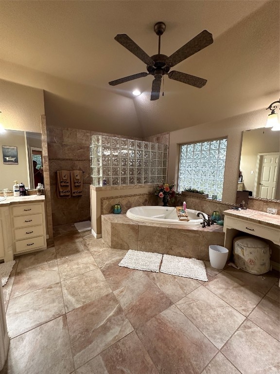 bathroom with tile flooring, vanity, ceiling fan, lofted ceiling, and tiled tub