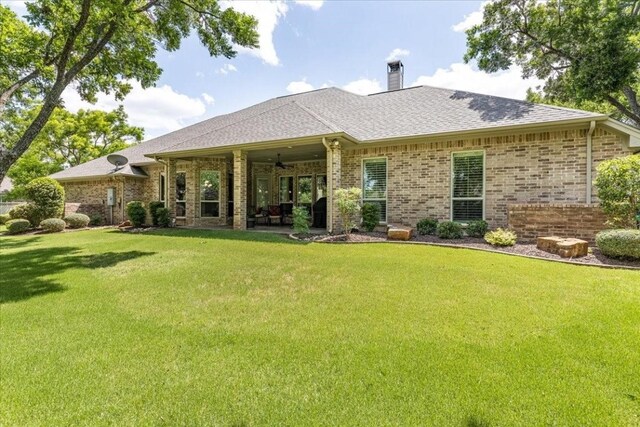 rear view of property featuring ceiling fan, a patio area, and a yard