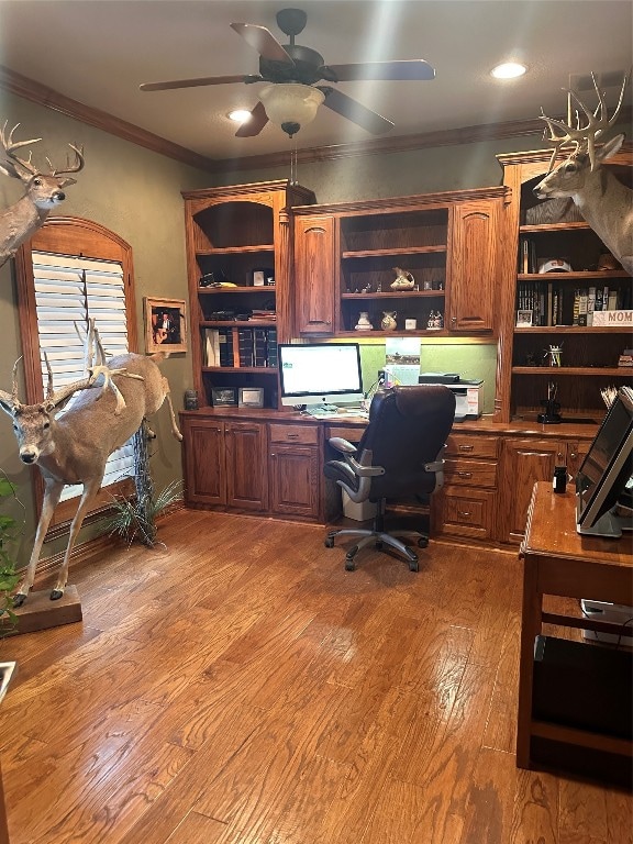 office area with crown molding, light hardwood / wood-style floors, ceiling fan, and built in desk