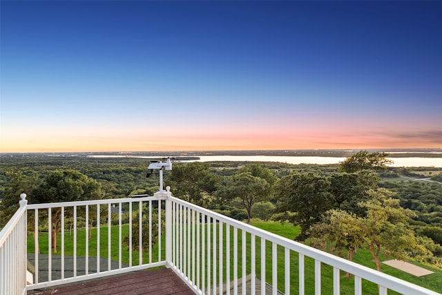 balcony at dusk featuring a water view