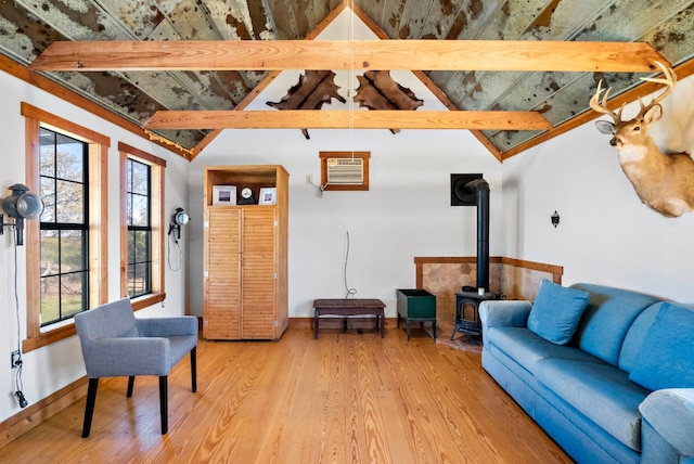 living room with light hardwood / wood-style flooring, lofted ceiling with beams, a wall unit AC, and a wood stove