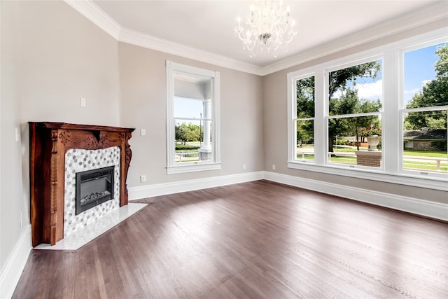 unfurnished living room with a tiled fireplace, ornamental molding, dark hardwood / wood-style floors, and a chandelier